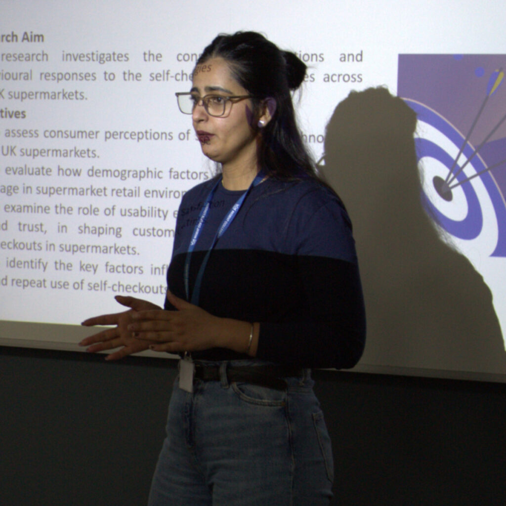 An RCL BA student delivering a presentation in a classroom lit only by a projector.