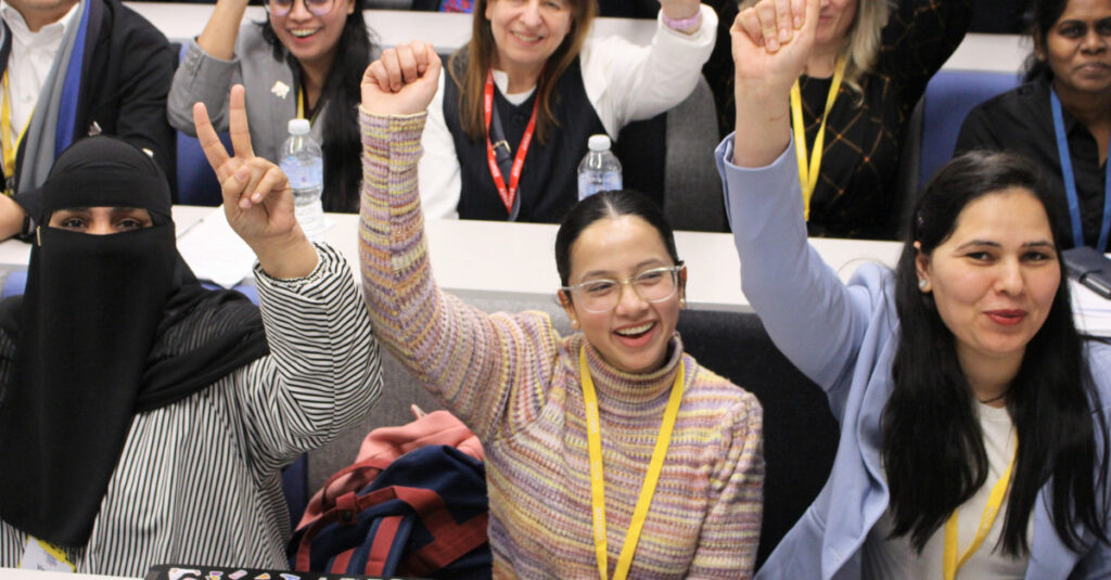 RCL School of Business staff and students smiling and cheering at the Fitzrovia Campus lecture theatre.