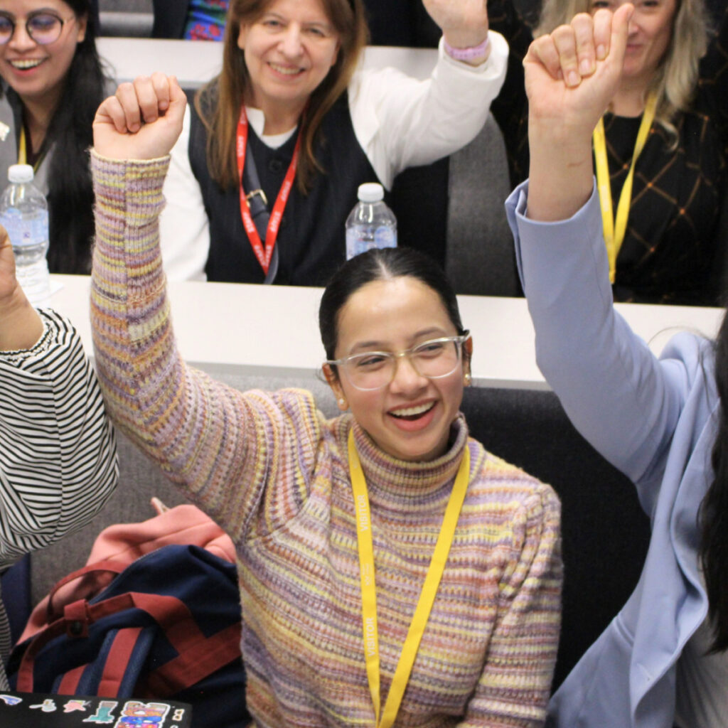 RCL School of Business staff and students smiling and cheering at the Fitzrovia Campus lecture theatre.
