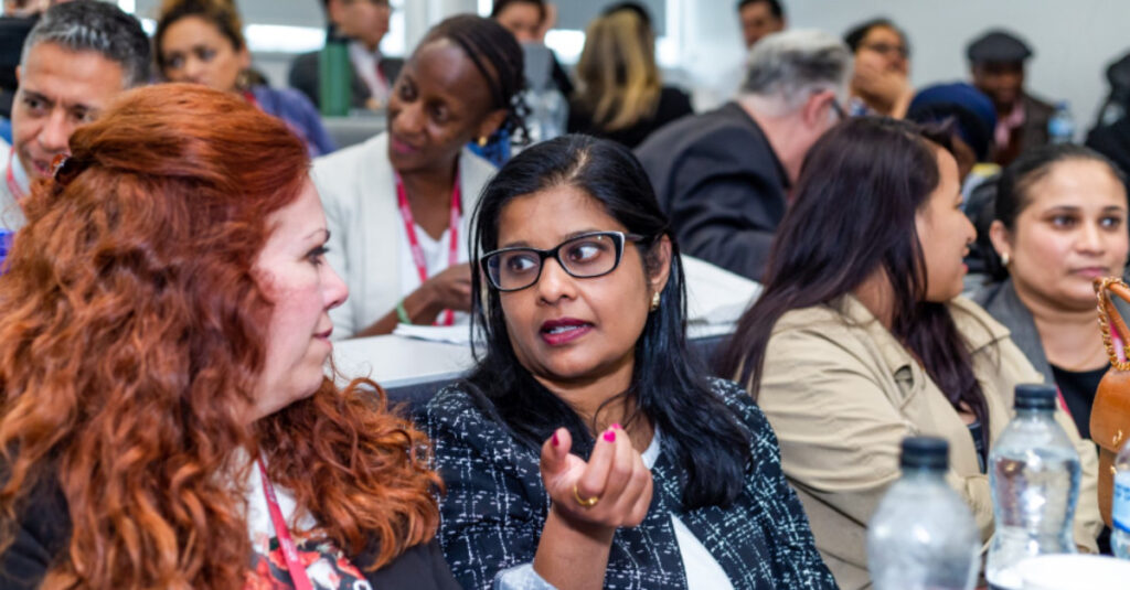 Attendees at Regent College London's Learning and Teaching Conference converse in the auditorium.